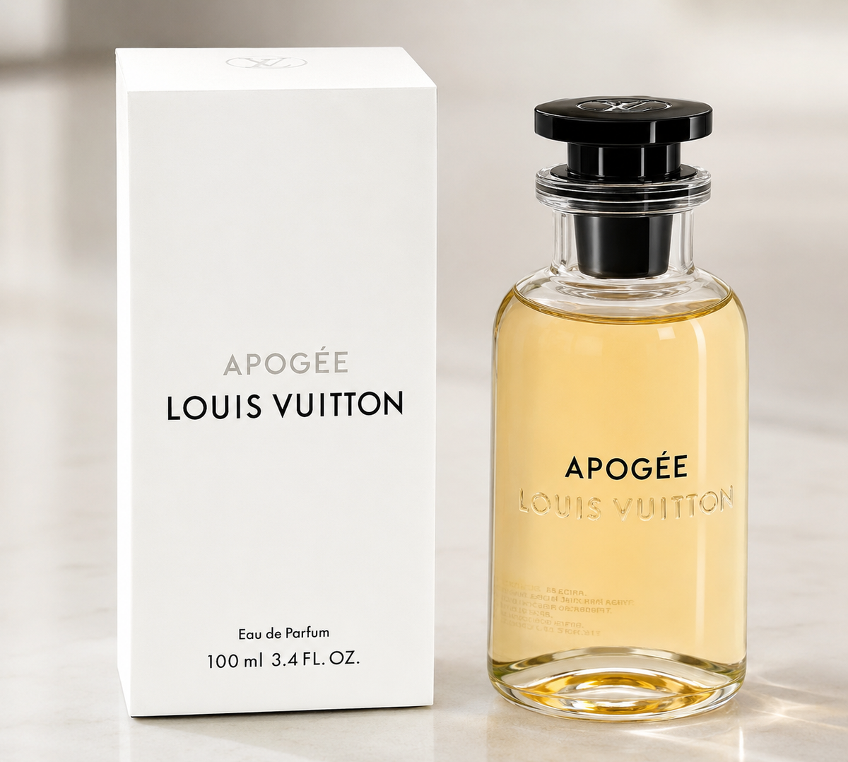 Louis Vuitton Apogée Eau de Parfum bottle with pale golden-yellow liquid next to its white packaging box, set against a soft, light gray marble background.