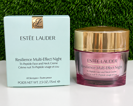Estée Lauder Resilience Multi-Effect Night cream shown with its light blue outer box and the pink glass jar with a gold cap, set against a green grass-like background.