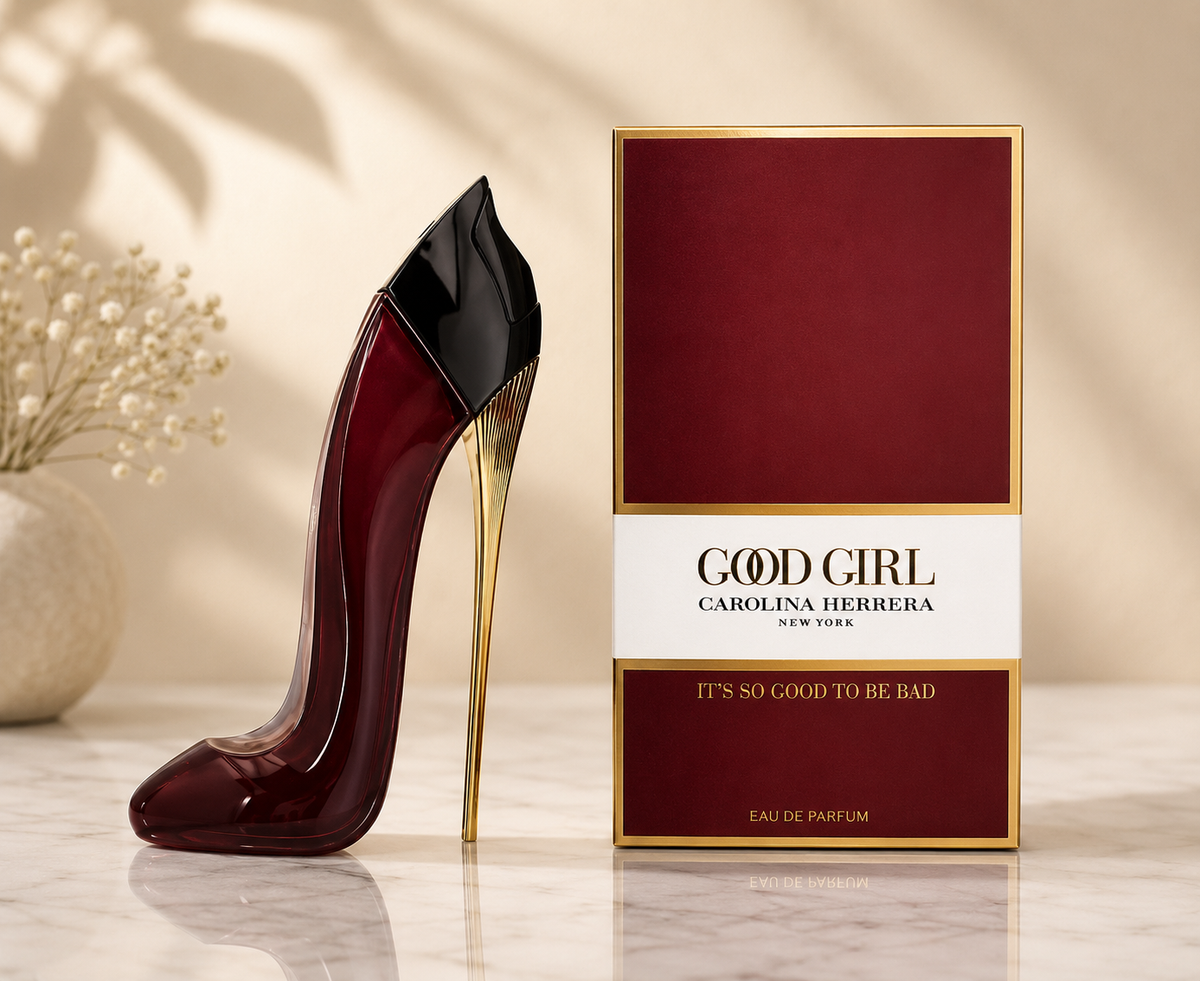 Carolina Herrera Good Girl Eau de Parfum bottle shaped like a high-heeled shoe in deep burgundy and black with a gold heel, displayed next to its matching burgundy and gold packaging box on a marble surface.